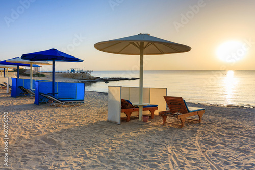 Fototapeta Naklejka Na Ścianę i Meble -  Sun loungers with umbrellas on the beach in Marsa Alam at sunrise, Egypt
