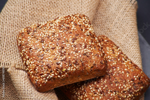 Two freshly baked rustic square shaped bread buns with sesame seeds extremely close up on the vintage rustic country style sackcloth photo