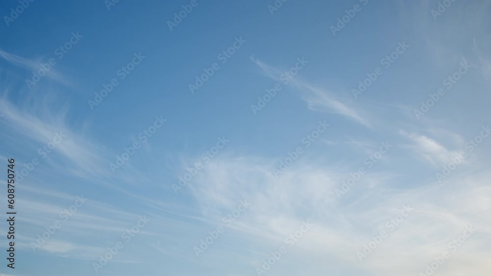 The blue sky is a tranquil and soothing setting for long and thin cirrus clouds that slowly pass by, bringing a sense of calm and serenity.