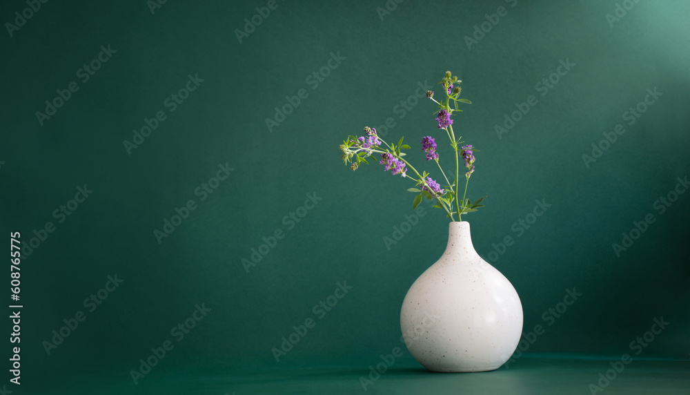 wild purple flowers in white modern vase on green background wild purple flowers in white modern vase on green background