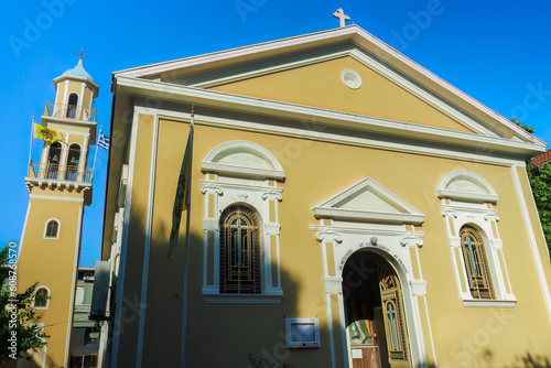 Orthodox colorful church facade of Saint Spiridon with a bell tower and Greek and Byzantine flags waving in Argostolion Town on the Ionian Island of Cephalonia Greece. photo