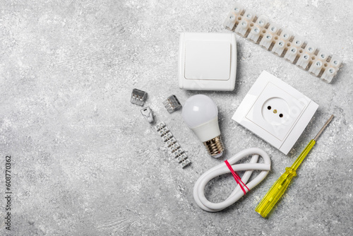 Electrician equipment on marble background with copy space.Top view.Electrician tool set.Multimeter, tester,screwdrivers,cutters,duct tape,lamps,tape measure and wires.Flet lay. photo