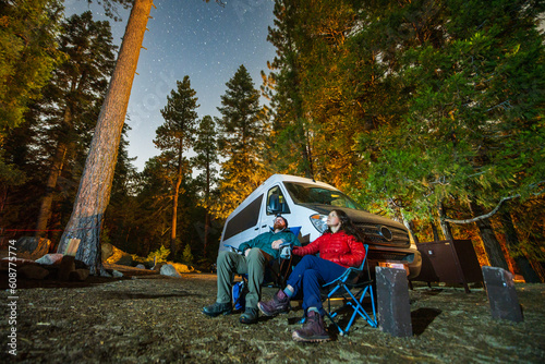 Couple gazes at the stars while camping with their van.