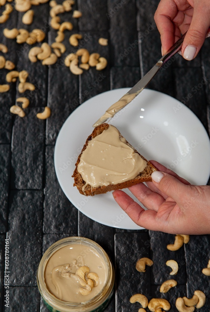 female hands spread nut butter with a knife on bread female hands spread nut butter with a knife on bread
