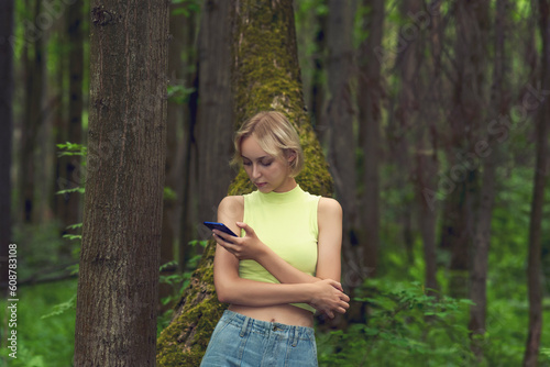 young woman with smartphone in natural forest park
