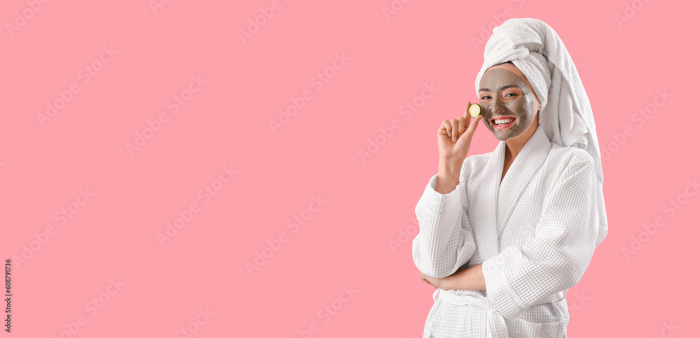 Young woman with applied clay mask and cucumber slice on pink background with space for text