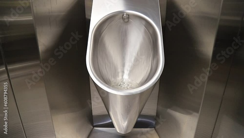 Sanitary metal urinal, toilet bowl in public bathroom with hygienic automatic water saving electronic flush. Urinal with urine sensor. Inductive flush toilet. WC