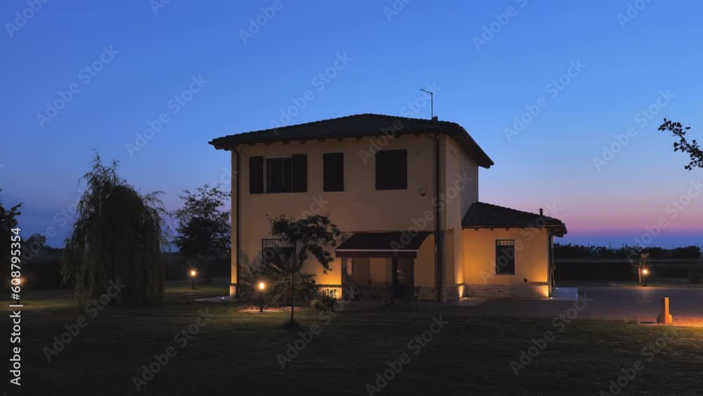 Establishing shot of a residential house with garden turning on the lights at dusk,automatic home lighting system twilight turn on sunset