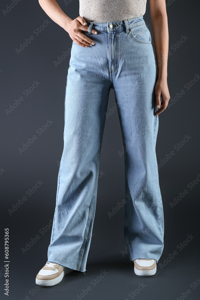 Young woman in stylish jeans on dark background Young woman in stylish jeans on dark background