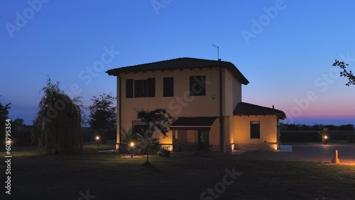 Establishing shot of a residential house with garden turning on the lights at dusk,automatic home lighting system twilight turn on sunset