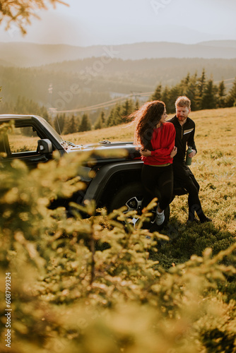 Young couple relaxing by a terrain vehicle hood at countryside