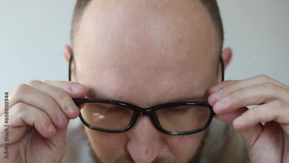 Young man with a beard puts on glasses smiling Young man with a beard puts on glasses smiling
