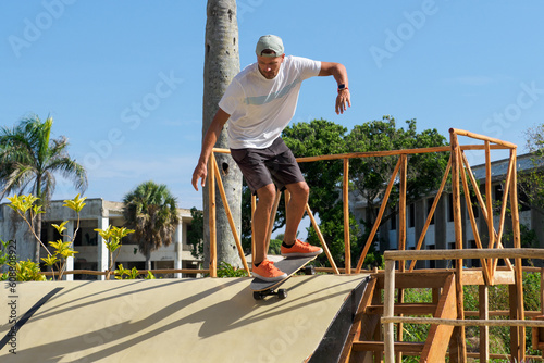 Skateboarder rides down on skateboard in skate park.
