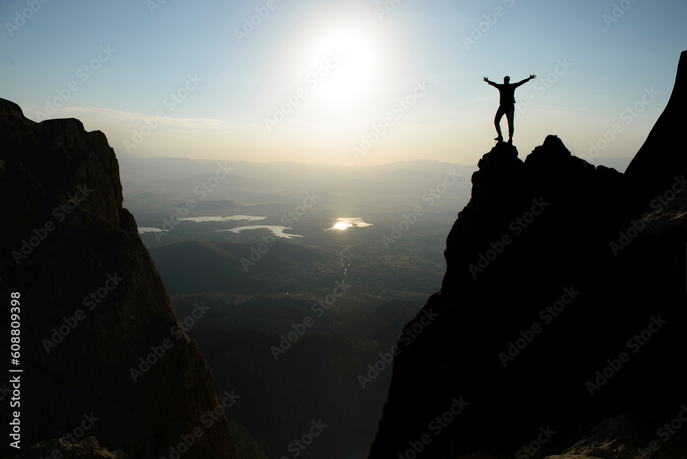 silhouette of brave and successful mountaineer on jagged cliffs