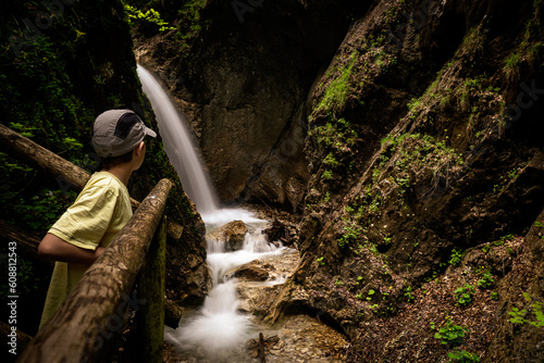 View of a boy watching white water cascading down the rocks at the rugged wilderness of the Dr. Vogelgesang-Klamm gorge in Spital am Pyhrn, Austria
