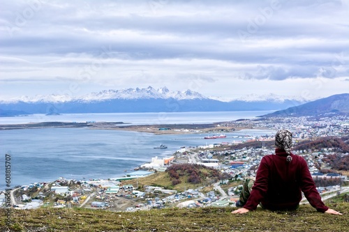 Photo of a person sitting on top of a grass-covered hill in Ushuaia, Argentina, Tierra del Fuego