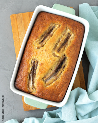 Banana bread. Freshly baked aromatic bread in a ceramic mold on a wooden board. Gray background