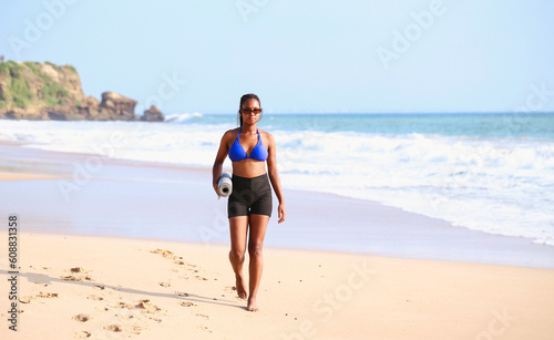 Young latina woman of african american descent doing yoga on the beach.Afro style hair. exercises. Young african american woman doing yoga exercises with sport clothes by the sea.