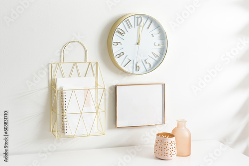 A neutral-colored wall with a clock and a shopping bag hanging from a hook photo