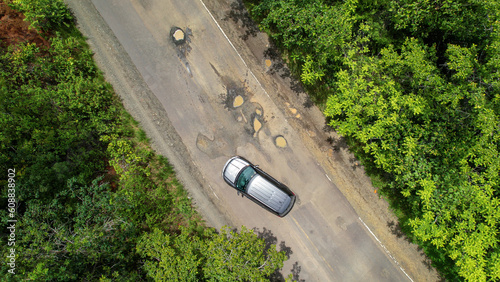 AERIAL TOP DOWN: Careful driving of car that tries to avoid dangerous road pits