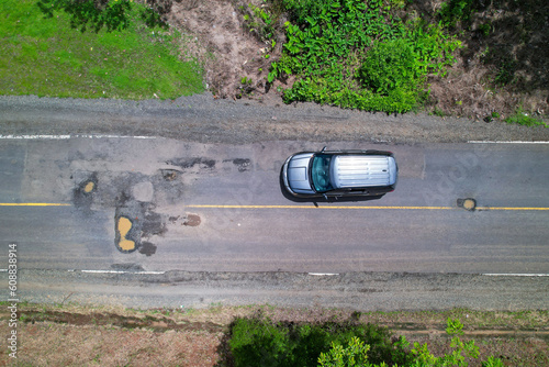 AERIAL TOP DOWN: Car drives carefully in order to avoid hazardous road dents