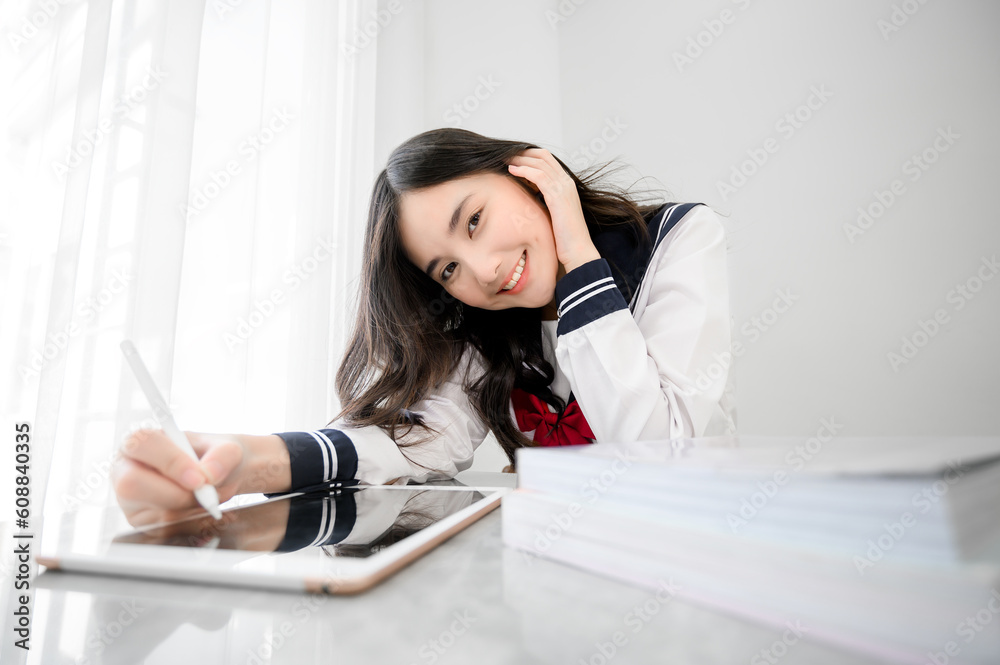 Obraz premium happy cheerful asian girl in japanese student uniform with tablet for online study