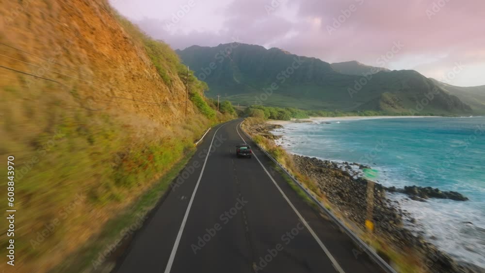 Tourists traveling by Oahu island Hawaii USA. Car driving along cinematic coastline. Aerial road above dramatic rocky ocean shore towards green volcanic mountains. Background of Happy summer vacation Tourists traveling by Oahu island Hawaii USA. Car driving along cinematic coastline. Aerial road above dramatic rocky ocean shore towards green volcanic mountains. Background of Happy summer vacation