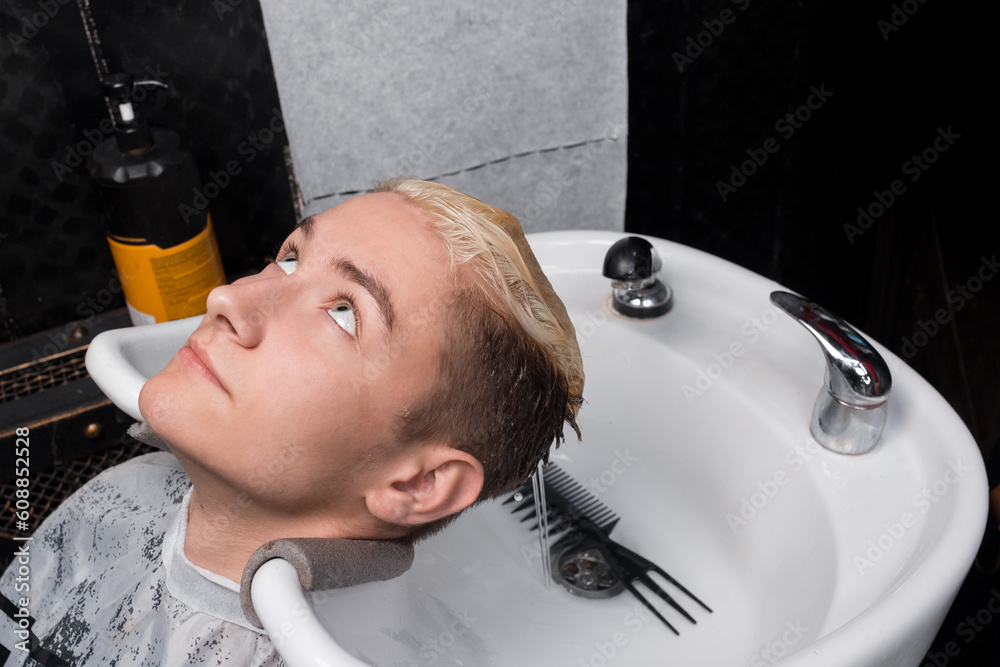 Young handsome guy barbershop customer lying on the sink after washing his hair before getting a haircut in a barbershop hairdresser Young handsome guy barbershop customer lying on the sink after washing his hair before getting a haircut in a barbershop hairdresser