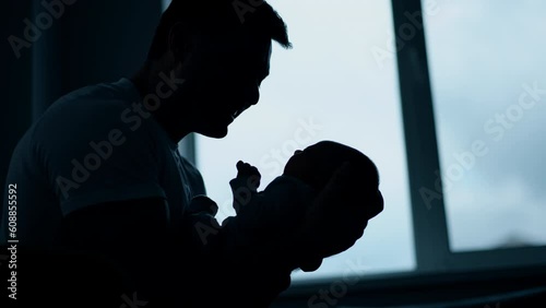 Father canoodling his little baby boy. Silhouettes of a dad with a child in front of the window. photo