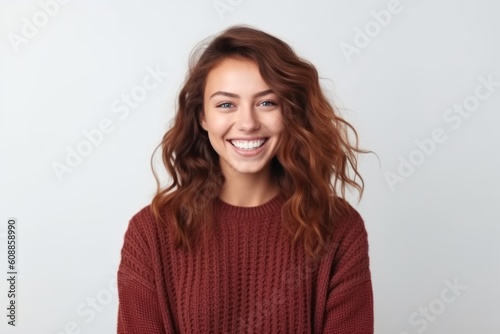 Portrait of a smiling young woman in sweater looking at camera over white background © Robert MEYNER