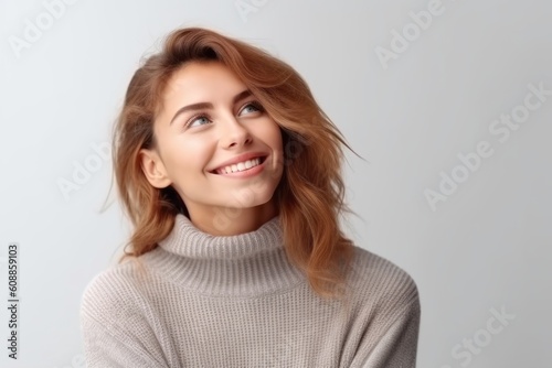 Portrait of a beautiful young woman in sweater on grey background.