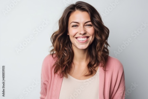 Portrait of a smiling young woman looking at camera over gray background