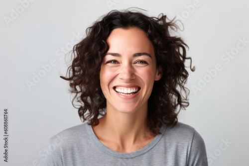 Close up portrait of a beautiful young woman laughing on gray background.