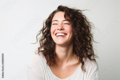 Portrait of a beautiful young woman with curly hair laughing over white background