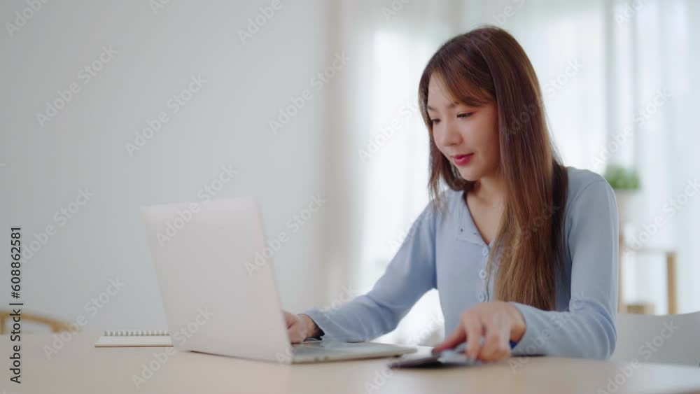 Young asian woman happy working on computer laptop and hand typing chat message on mobile smartphone at home. Video call, Online meeting Young asian woman happy working on computer laptop and hand typing chat message on mobile smartphone at home. Video call, Online meeting