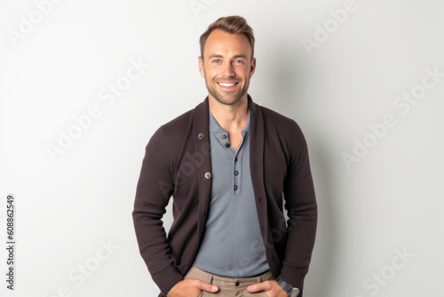 Handsome young man standing with hands in pockets on white background