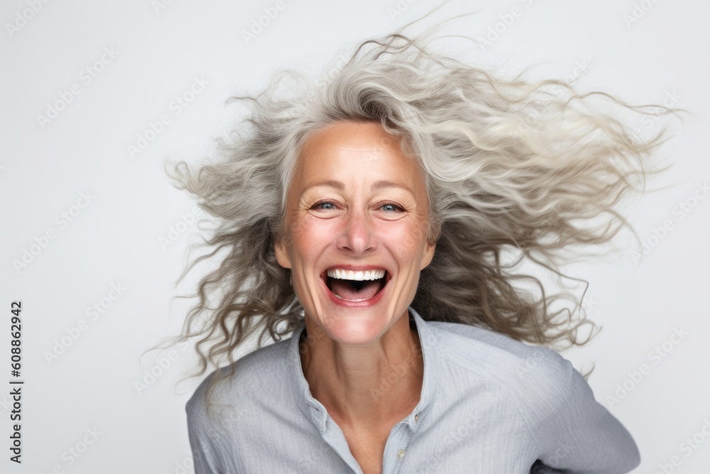 Portrait of a happy senior woman with flying hair over gray background Portrait of a happy senior woman with flying hair over gray background