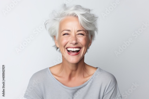 Portrait of happy senior woman with white hair laughing over white background