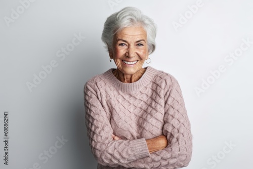 Portrait of smiling senior woman with arms crossed standing against grey background