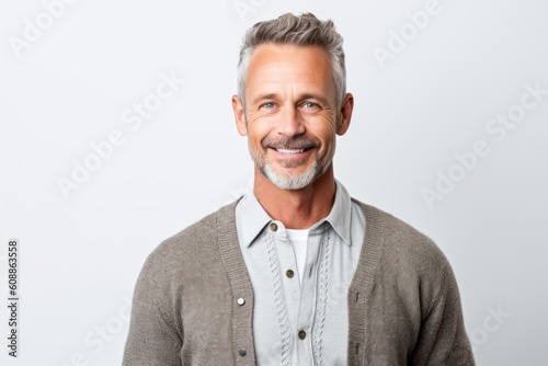 Portrait of handsome mature man looking at camera and smiling while standing against white background