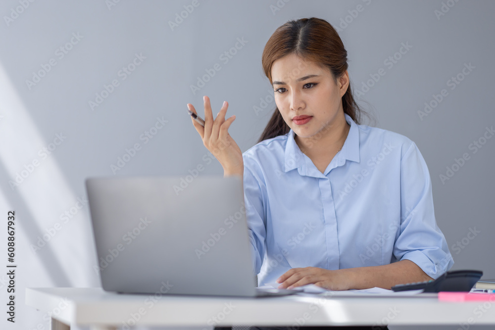 Portrait of tired young business Asian woman work with documents tax laptop computer in office. Sad, unhappy, Worried, Depression, or employee life stress concept Portrait of tired young business Asian woman work with documents tax laptop computer in office. Sad, unhappy, Worried, Depression, or employee life stress concept