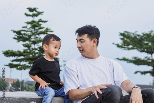 Father talking with his son in outdoors at the park enjoying time together on weekend. Family relationship and concept of Fathers Day 