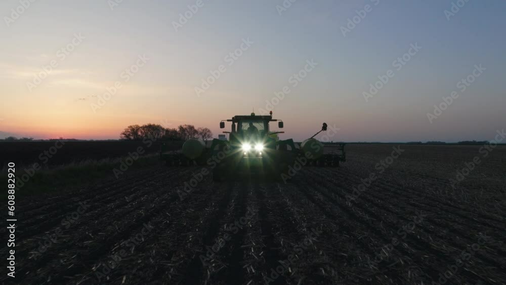 Aerial, tractor with strip till toolbar plowing farm field in the morning to prepare for seed planing Aerial, tractor with strip till toolbar plowing farm field in the morning to prepare for seed planing