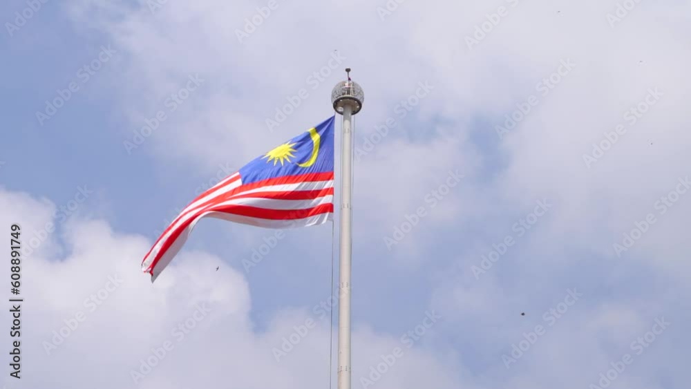 Cinematic view of Malaysian flag waving in slow motion against blue sky Cinematic view of Malaysian flag waving in slow motion against blue sky