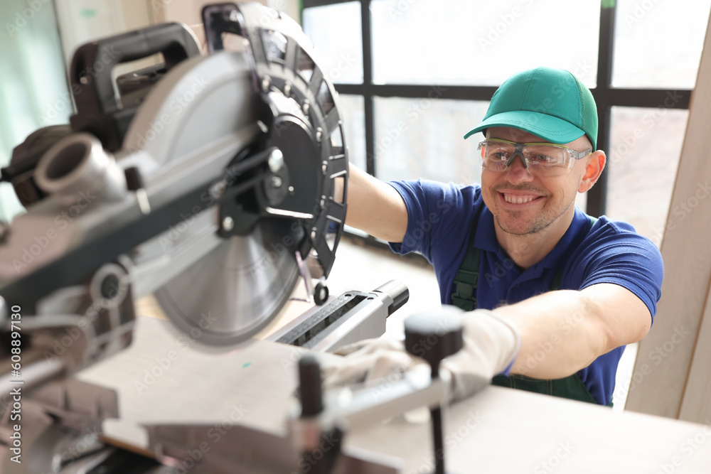 Carpenter with goggles cuts boards with sawing machine Carpenter with goggles cuts boards with sawing machine