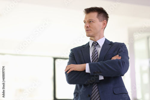 Thoughtful businessman with crossed arms looks aside
