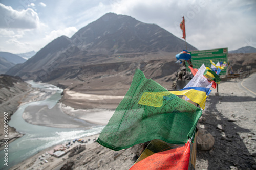 Sangam point. Sangam Valley is a 35 km (22 miles) drive from Leh,I ndia and is the confluence of the rivers Indus and Zanskar. Colorful flags on the roadside of Sangam Viewpoint in Sangam , Leh Ladakh