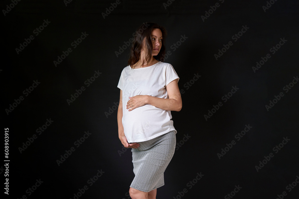 Happy pregnant woman with big belly posing on black background Happy pregnant woman with big belly posing on black background