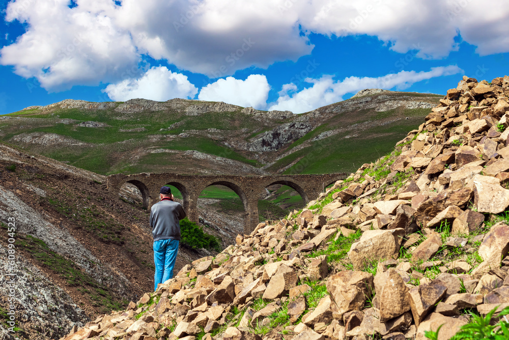 Photographer traveler takes pictures of an old stone bridge