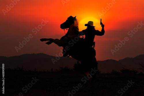 Silhouette of cowboy on horseback and sunset as background